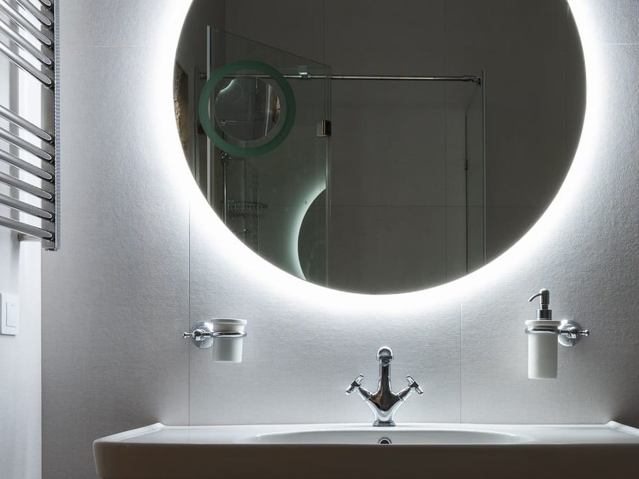 Miroir rond rétroéclairé dans une salle d'eau claire et carrelée