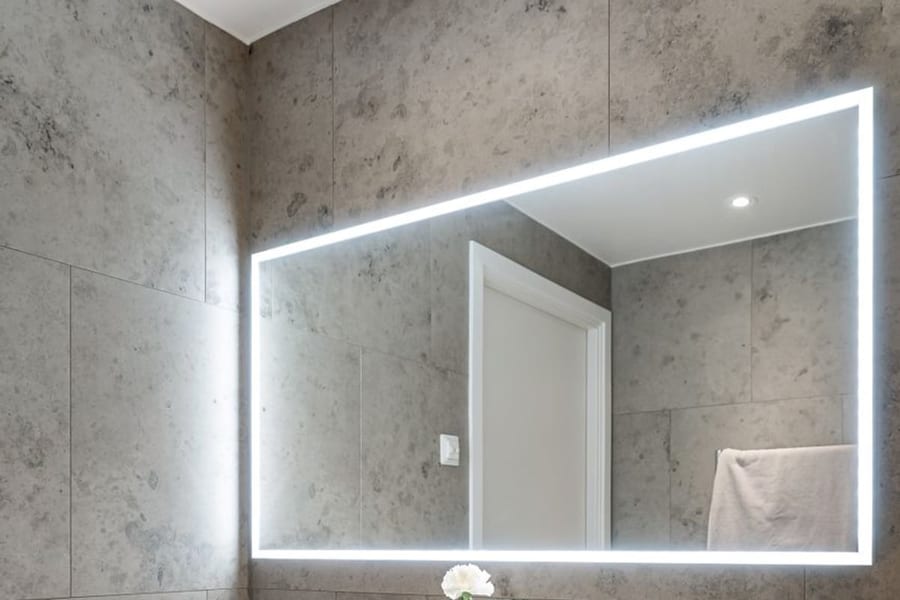 Salle d'eau en pierre claire avec miroir rétroéclairé sur toute la largeur